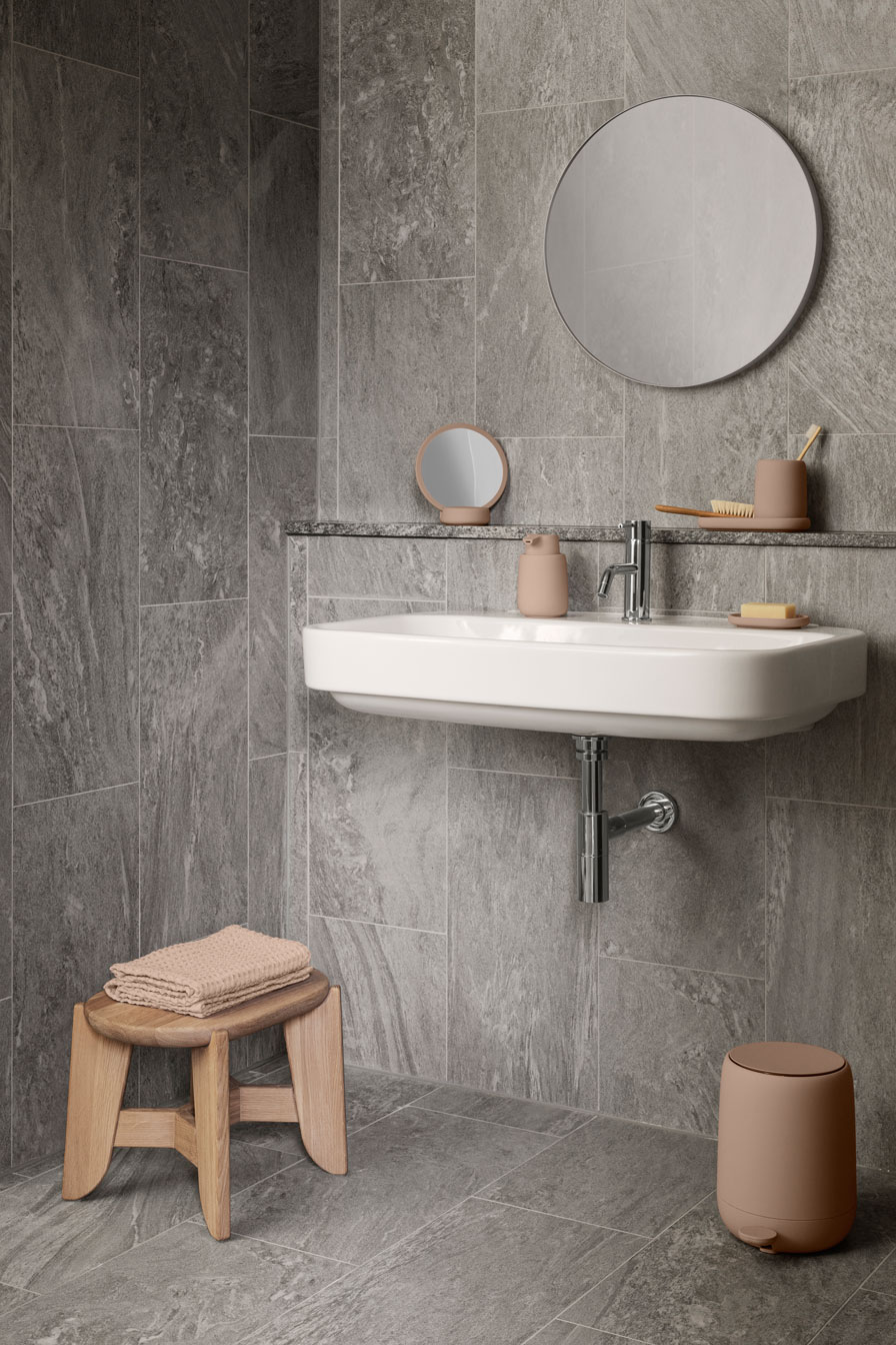 a bathroom setting showing the sink and mirror side with a wooden stool on the side with towels