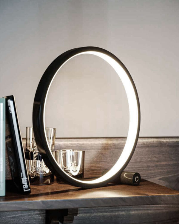 round table light next to some books on a side table. the lamp offers three dimmable brightness mode, touch activated