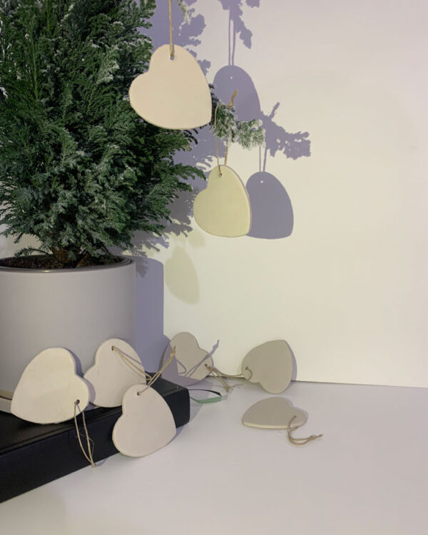 clay ornaments in white hanging from a small tree. shaped as a heart. set of 8