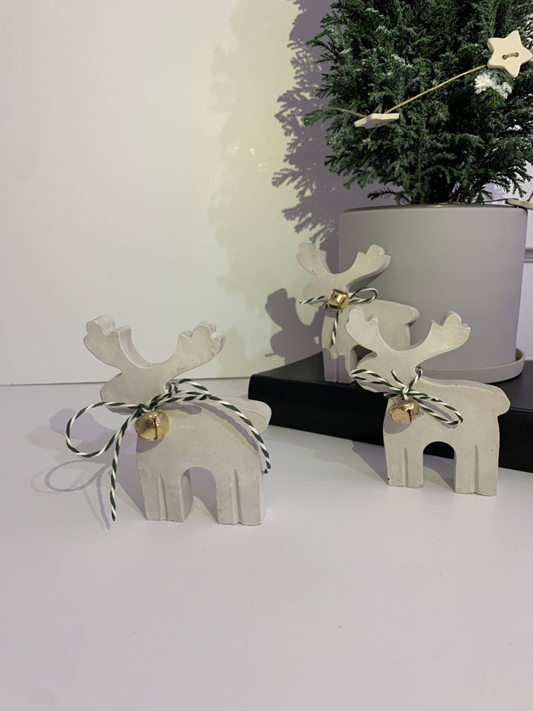 concrete reindeer in grey beige tone with a ropey Christmas cord and a gold small bell
