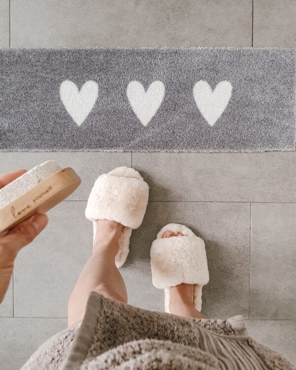 a grey doormat with 3 white hearts on it. 75cm x 25cm.
