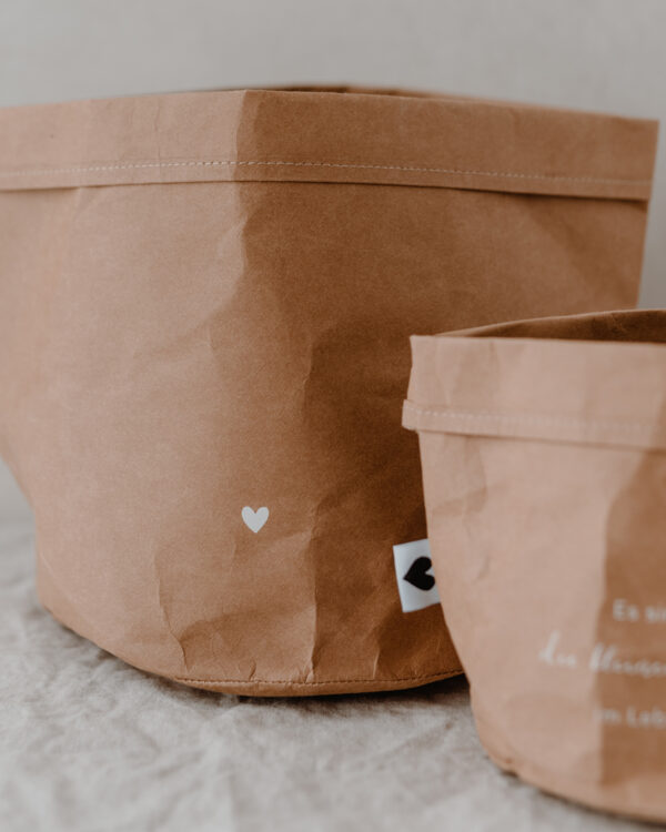 paper baskets in black colour. This set consists of two paper bags in different sizes. The larger paperbag is decorated with a heart. The smaller one bears the saying "It's the little things in life" in German.