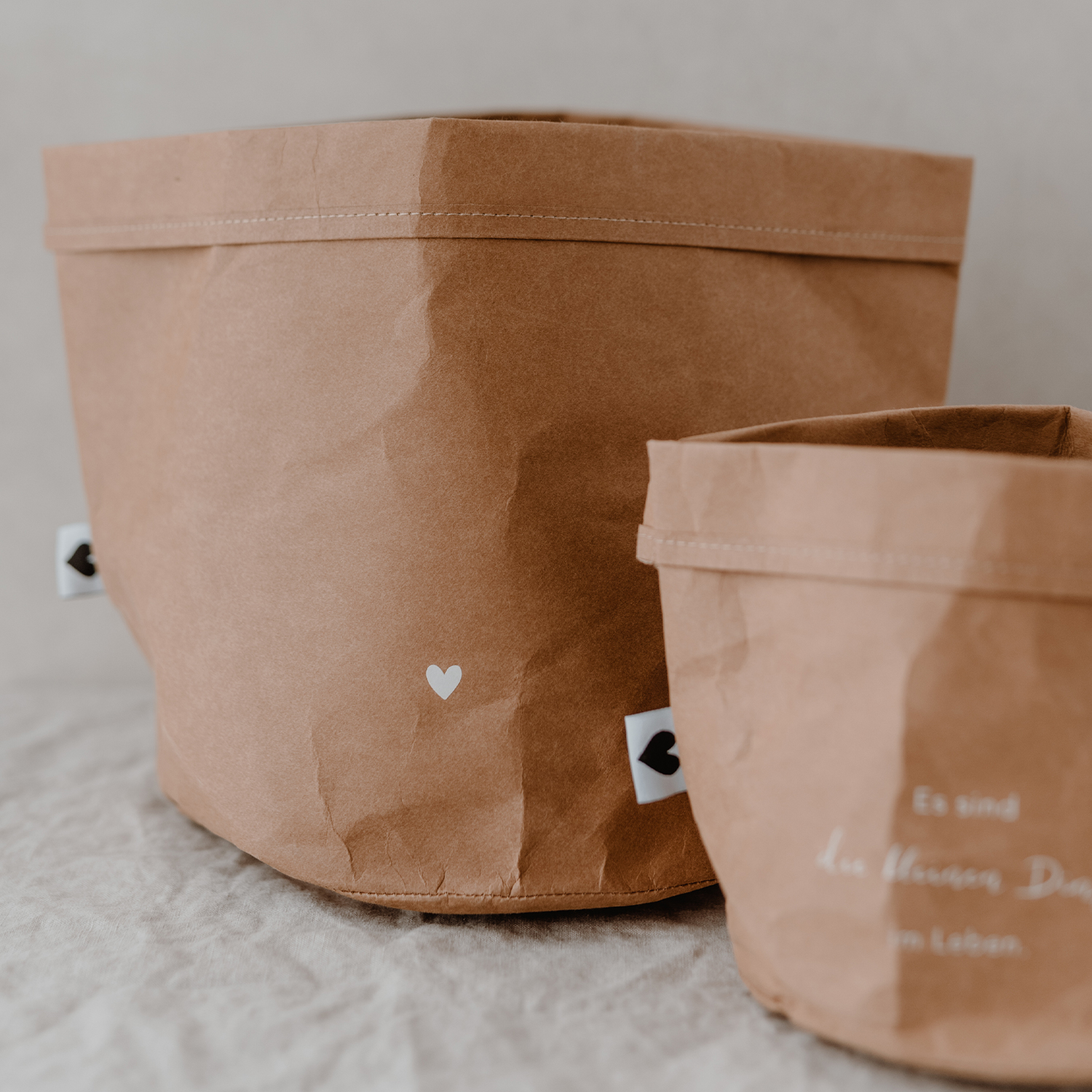 paper baskets in black colour. This set consists of two paper bags in different sizes. The larger paperbag is decorated with a heart. The smaller one bears the saying "It's the little things in life" in German.