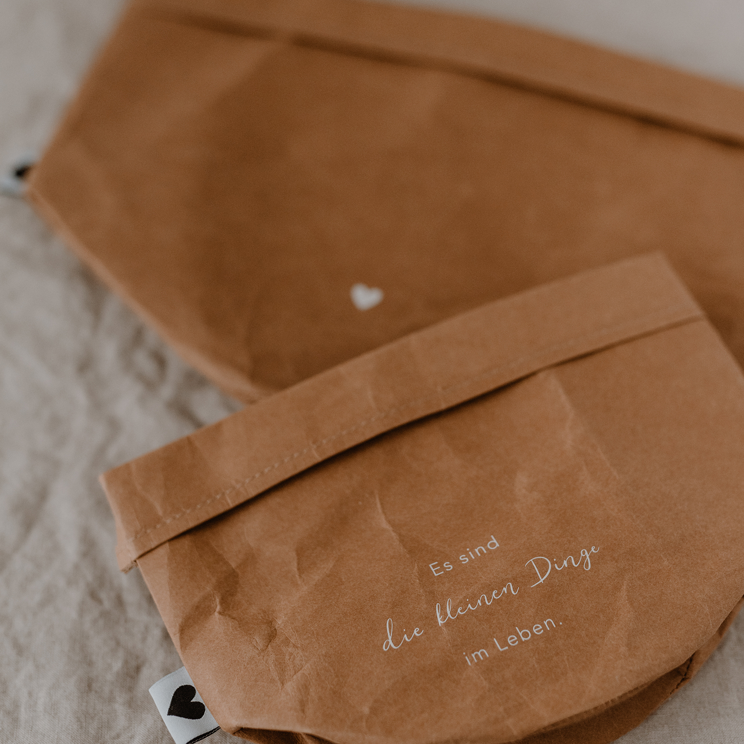 paper baskets in black colour. This set consists of two paper bags in different sizes. The larger paperbag is decorated with a heart. The smaller one bears the saying "It's the little things in life" in German.