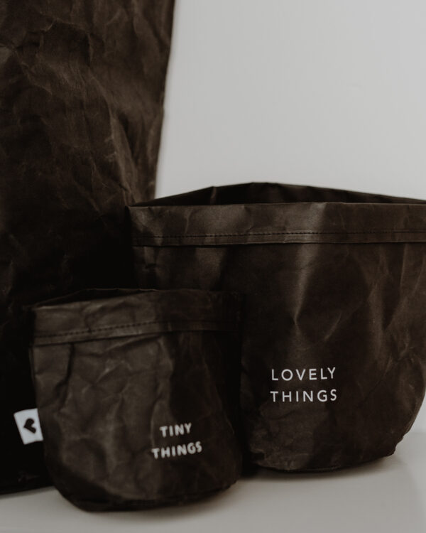 paper baskets in black colour. This set consists of two paper bags in different sizes. The larger paperbag bears the slogan "Lovely Things". The smaller paper bag "Tiny Things".