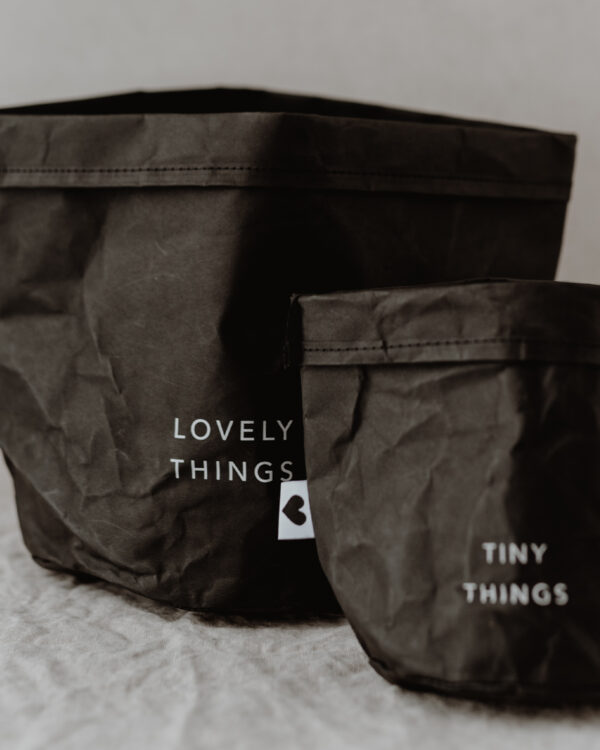 paper baskets in black colour. This set consists of two paper bags in different sizes. The larger paperbag bears the slogan "Lovely Things". The smaller paper bag "Tiny Things".