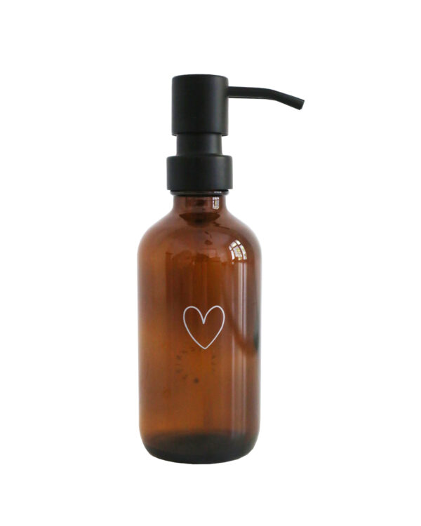 amber glass soap dispenser with an outline of a white heart engraved