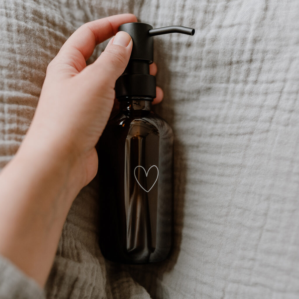 amber glass soap dispenser with an outline of a white heart engraved