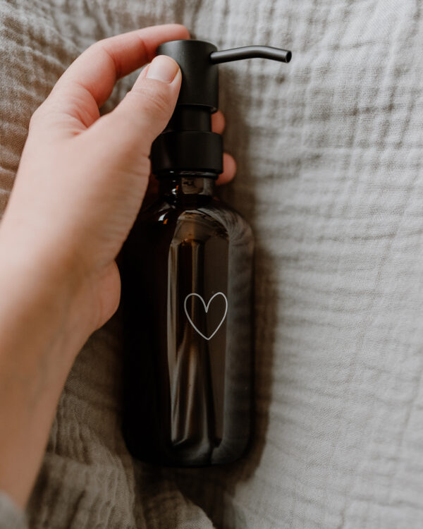 amber glass soap dispenser with an outline of a white heart engraved