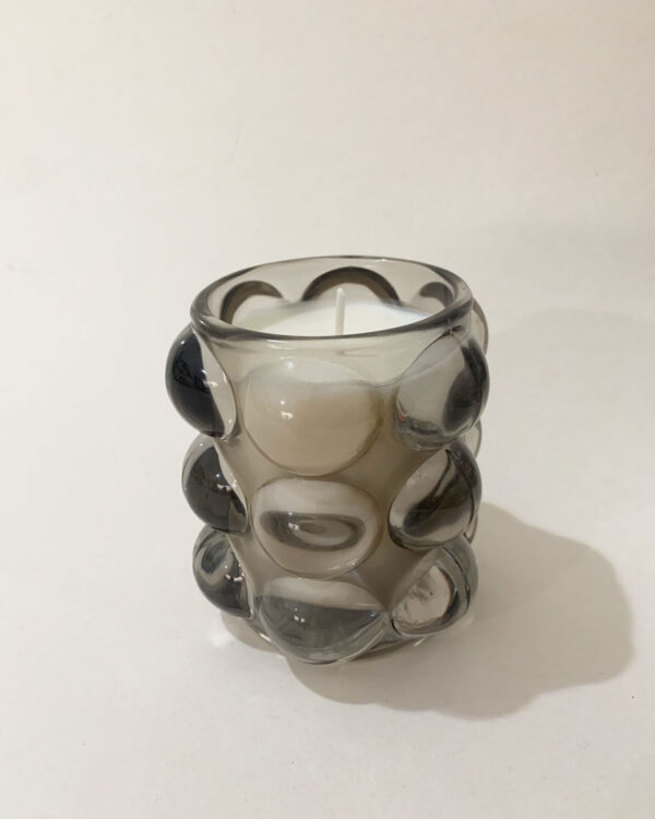 Image of a scented candle in a bubble glass vessel, emitting a warm glow. Each candle has a unique scent and is labeled with its corresponding fragrance. The glass vessel adds a touch of elegance to the overall presentation