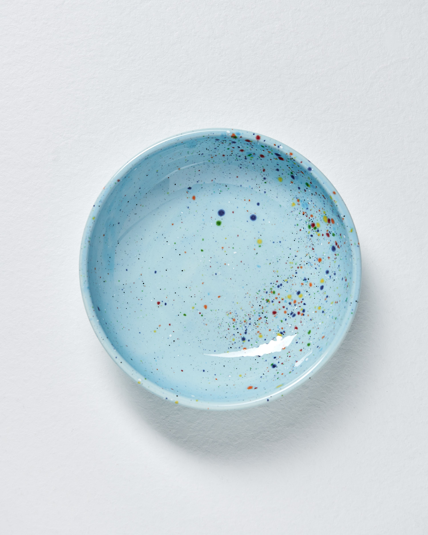 A collection of modern pasta bowls in various bright colours. The bowl in the image is a blue ceramic bowl with colourful spots.