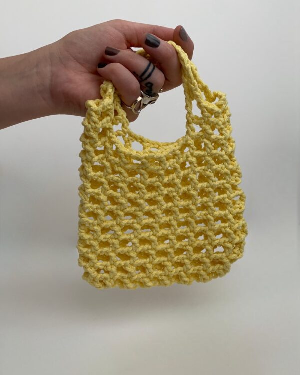 Close-up of a beautiful YELLOW crochet bag with a mesmerising mesh pattern. Perfect for a stylish and chic look.