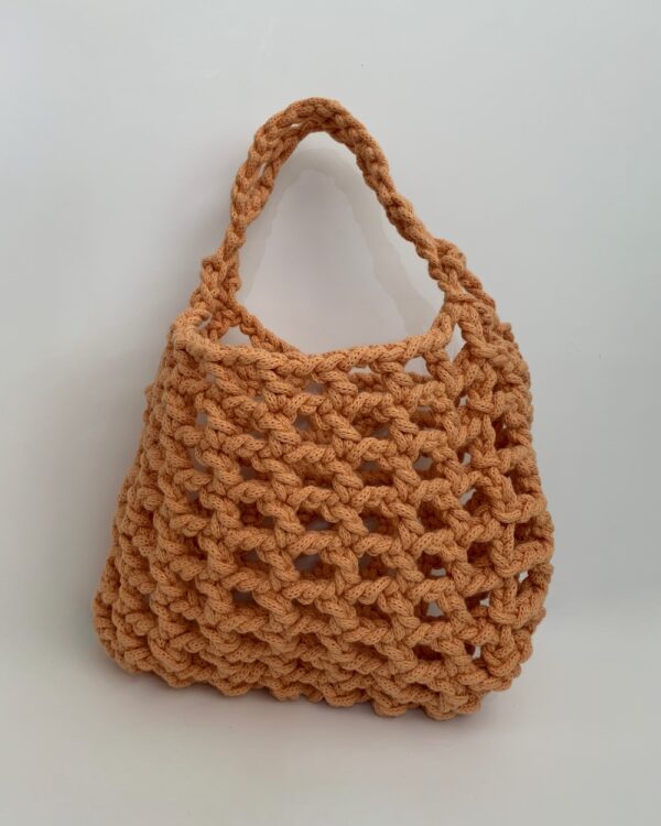 Close-up of a beautiful orange crochet bag with a mesmerising mesh pattern. Perfect for a stylish and chic look.
