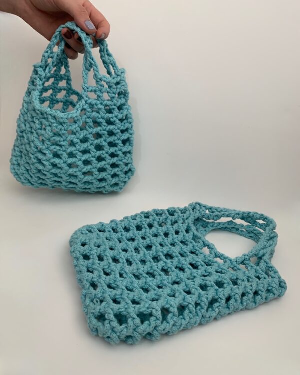 Close-up of a beautiful baby blue crochet bag with a mesmerising mesh pattern. Perfect for a stylish and chic look.