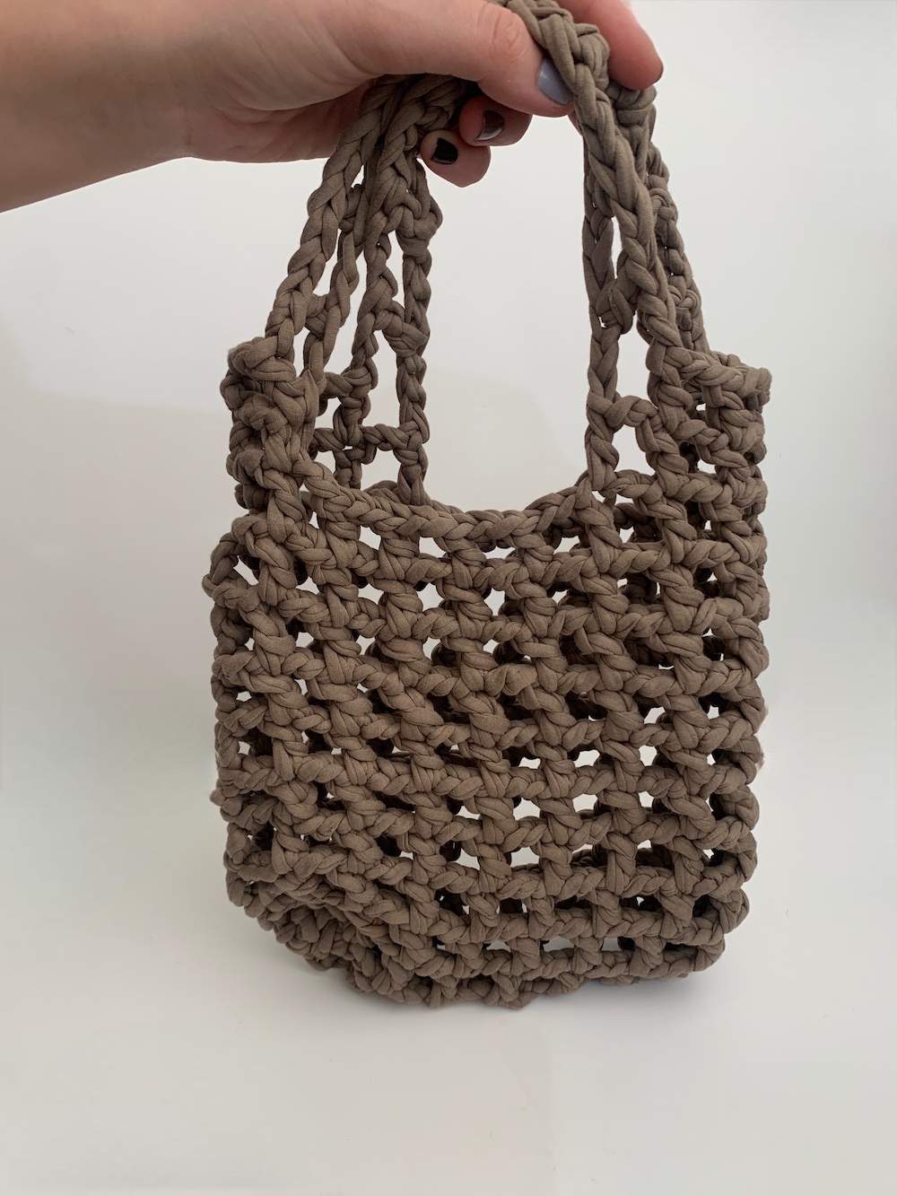 Close-up of a beautiful ASH-BEIGE crochet bag with a mesmerising mesh pattern. Perfect for a stylish and chic look.