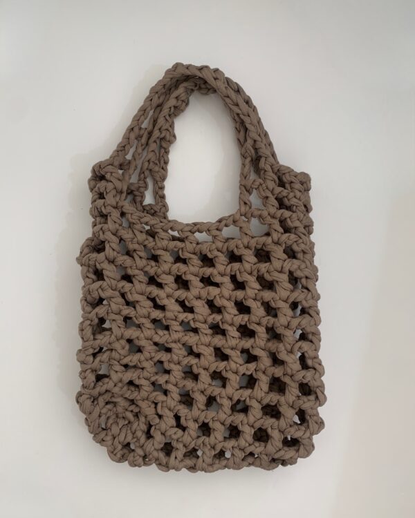 Close-up of a beautiful ASH-BEIGE crochet bag with a mesmerising mesh pattern. Perfect for a stylish and chic look.