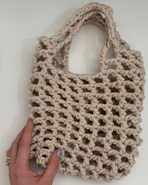 Close-up of a beautiful BEIGE crochet bag with a mesmerising mesh pattern. Perfect for a stylish and chic look.