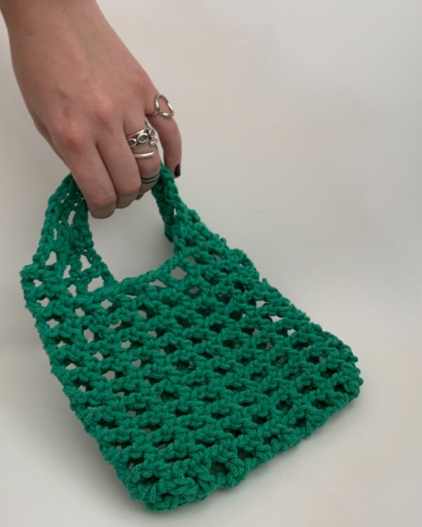 Close-up of a beautiful green crochet bag with a mesmerising mesh pattern. Perfect for a stylish and chic look.