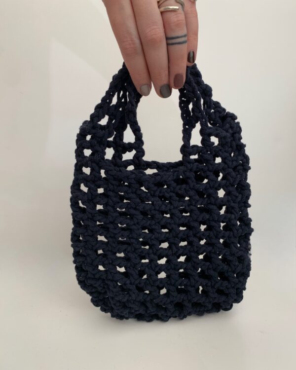 Close-up of a beautiful blue crochet bag with a mesmerising mesh pattern. Perfect for a stylish and chic look.