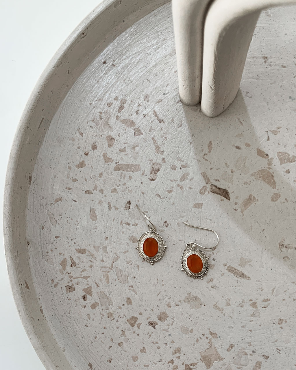 sterling silver earrings with a carnelian stone on a terrazzo tray