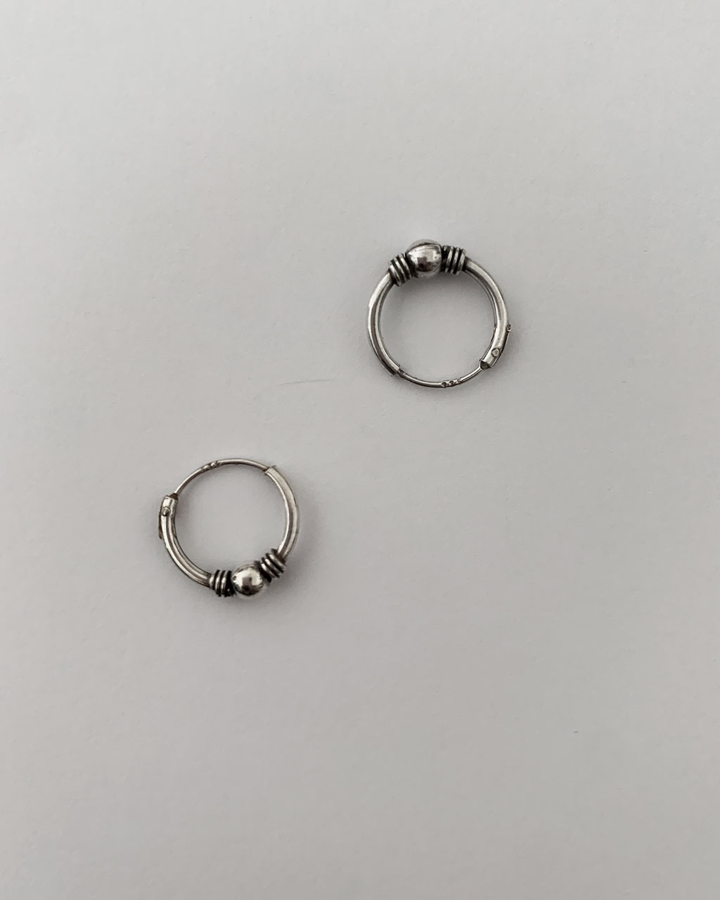 sterling silver hoop earrings with a bali design on a white background