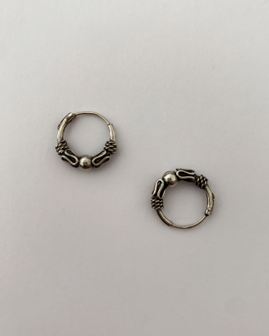 sterling silver hoop earrings with a bali design on a white background