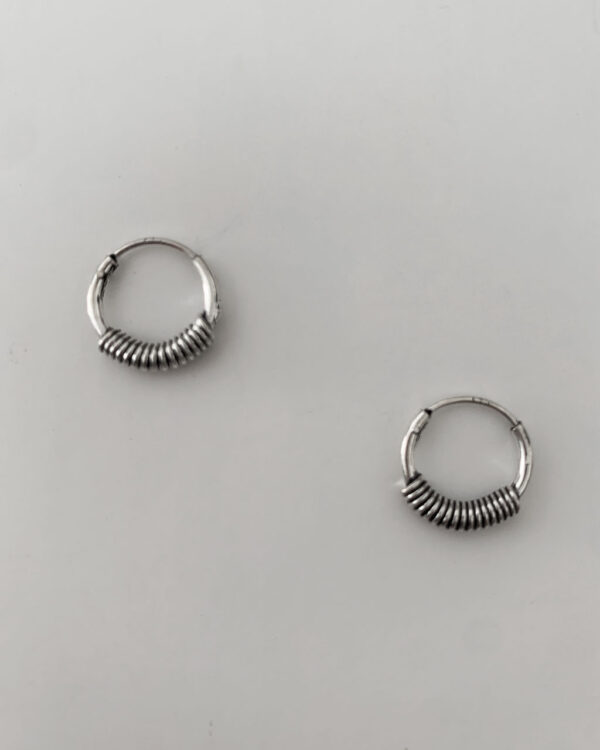 sterling silver hoop earrings with a bali design on a white background.