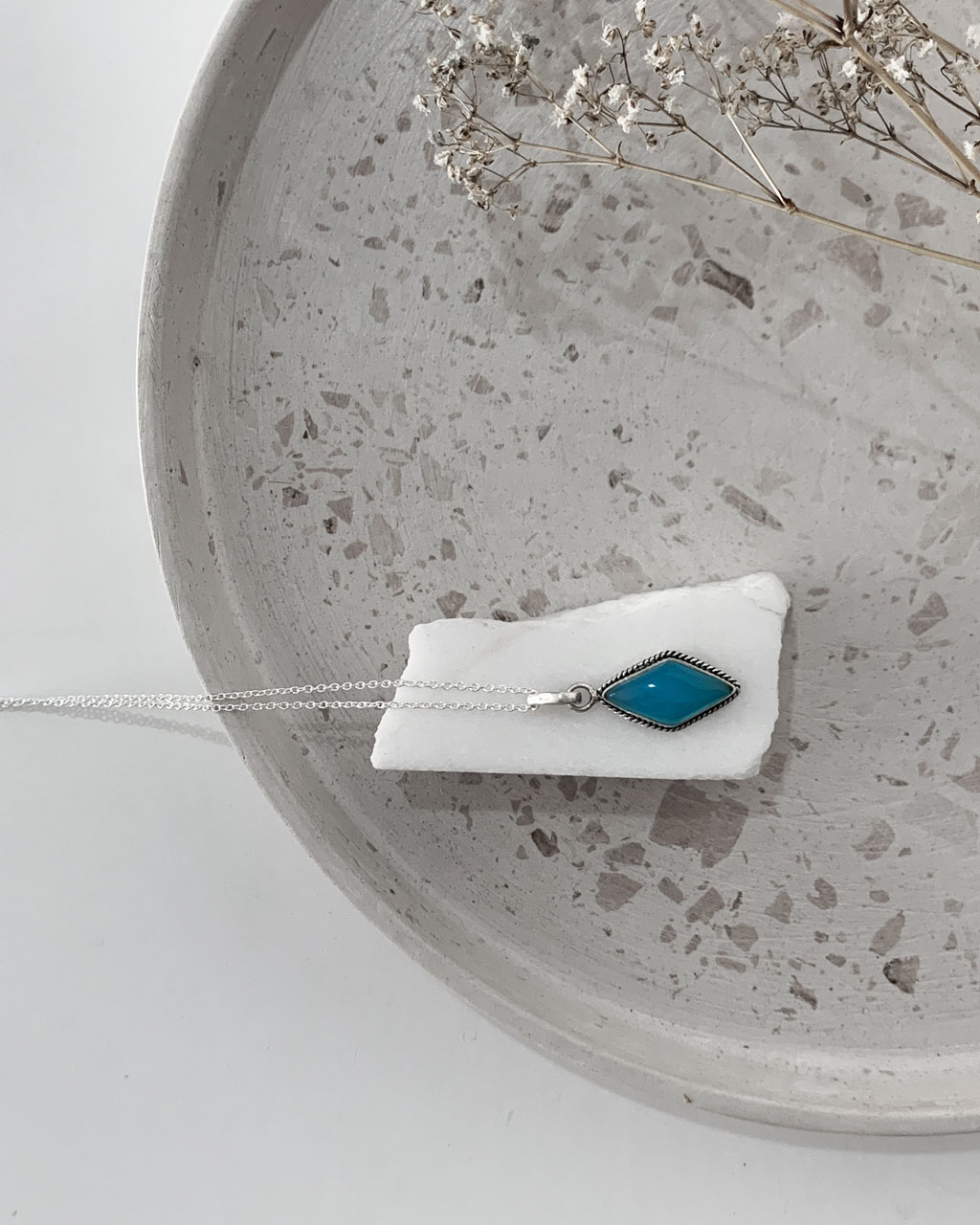 Aqua Chalcedony necklace on a white marble sitting on a terrazzo tray