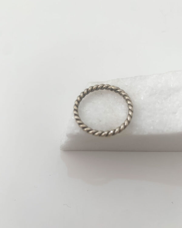 Close-up image of a shiny, sterile silver ring on a white marble on a white background.