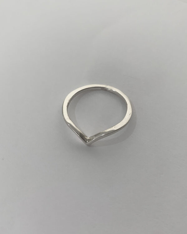 Close-up image of a shiny, sterile silver wishbone ring on a white background.