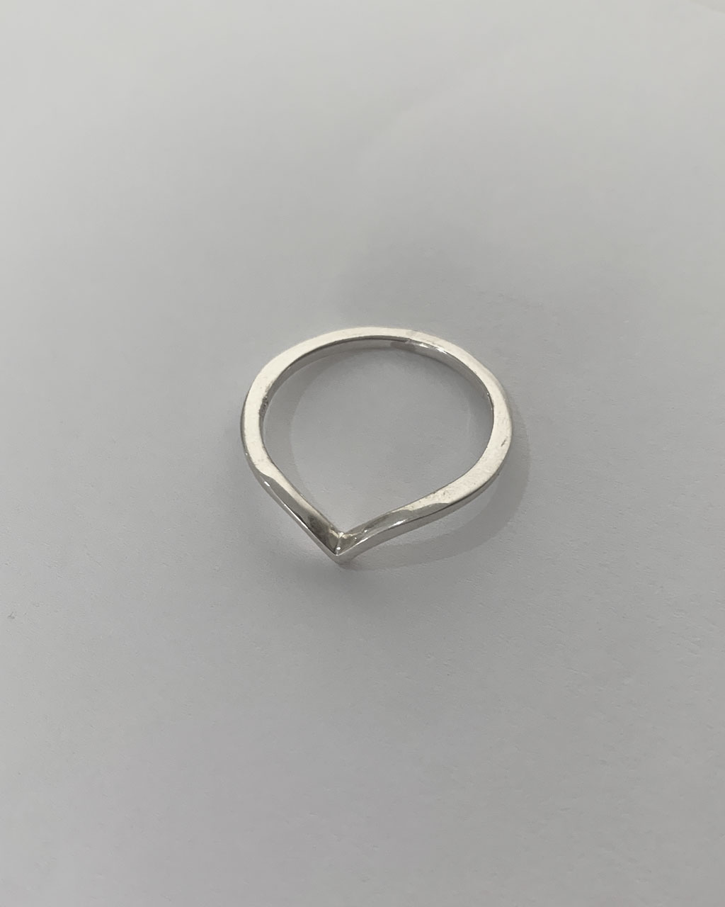 Close-up image of a shiny, sterile silver wishbone ring on a white background.