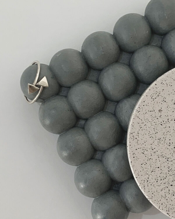 Close-up image of a shiny, sterile silver ring with arrows on both ends on a blue concrete coaster