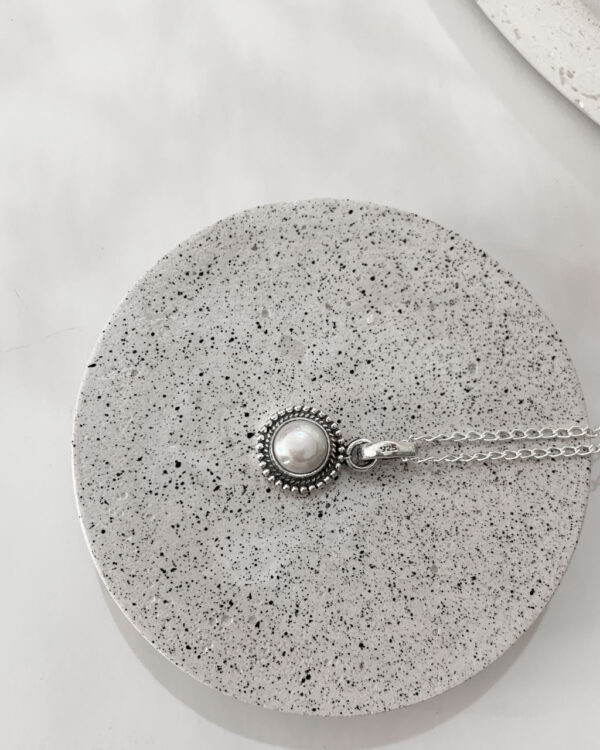 pearl necklace on a speckled coaster on a white background