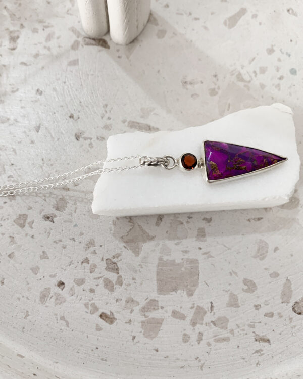 purple and copper garnet stone necklace on a white marble on a terrazzo tray