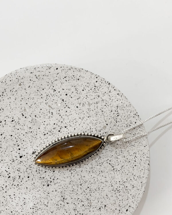 tiger eye stone necklace on a speckled coaster on a terrazzo tray