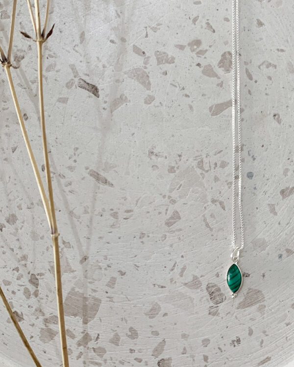 malachite stone necklace on a terrazzo tray
