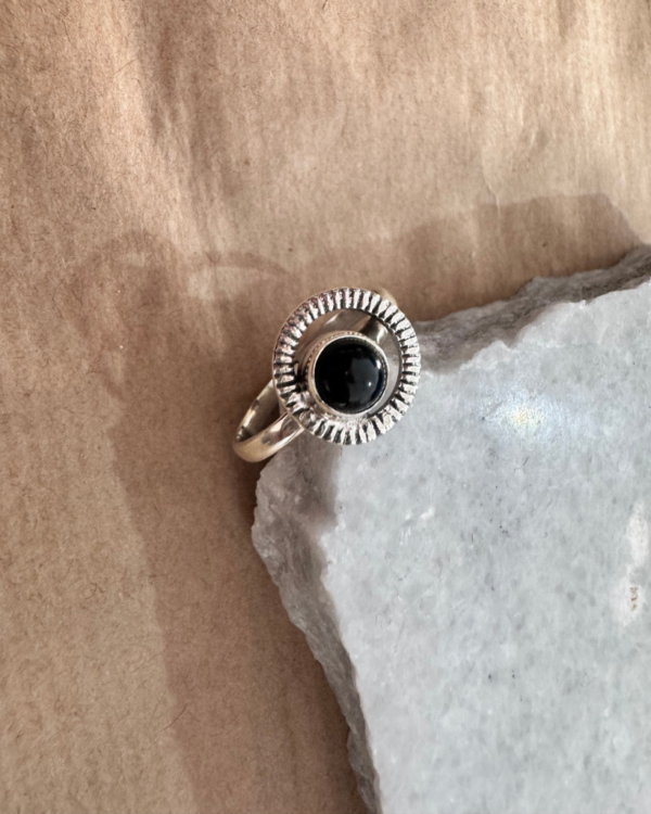 tunning black onyx ring featuring an intricate design with a circle around it. 2. This unique piece is perfect for adding a touch of elegance to any outfit, whether you're dressing up for a special occasion or simply want to elevate your everyday look.