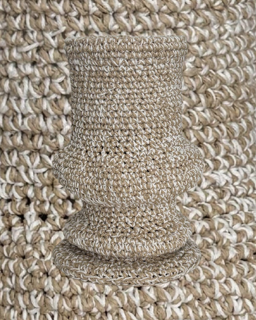This handmade crochet ivory vase is a charming decorative piece that adds a touch of warmth to any space. Crafted with care over five weeks using soft cotton yarn, it showcases intricate patterns and a unique design that stands out. Perfect for holding flowers or as a standalone accent, this vase is a delightful addition to your home decor.