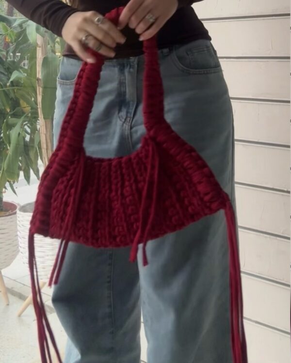 This handcrafted burgundy bag combines style and function with its chunky crochet texture. Made from soft t-shirt yarn, it easily transitions from shoulder to handbag, making it the perfect companion from day to night. Features a stretchy yet sturdy construction that adapts to your needs.