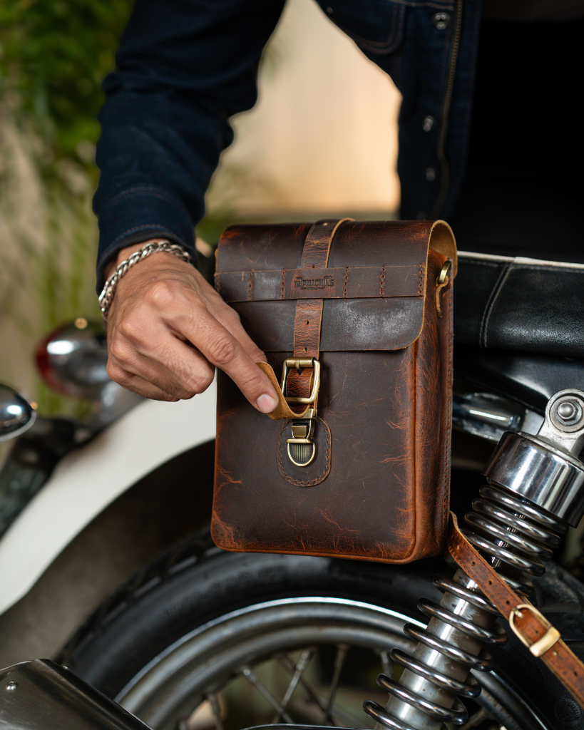 Premium leather sling bag with quick-release mounting (motorcycle compatible), one-click opening, and included rain cover. Handcrafted and built to last, developing a unique patina over time. Perfect for everyday carry and more.