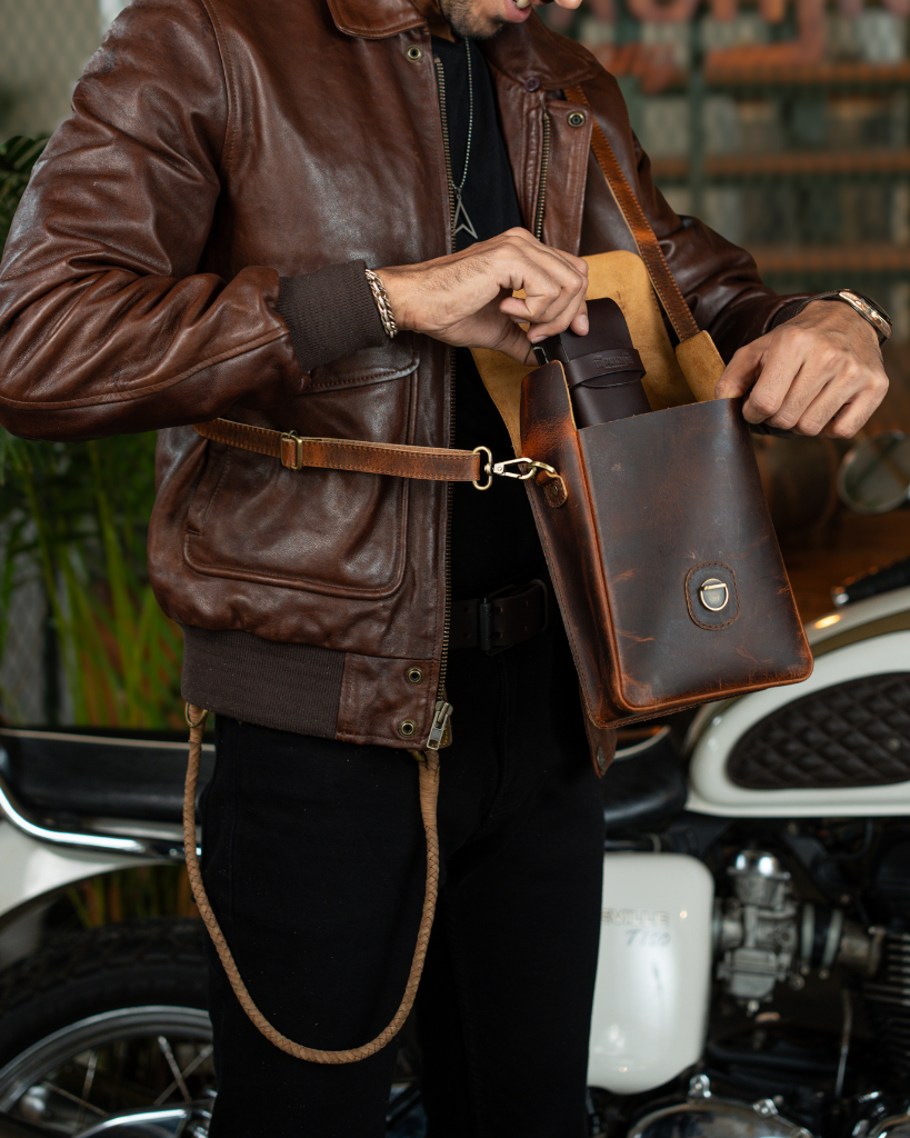 Premium leather sling bag with quick-release mounting (motorcycle compatible), one-click opening, and included rain cover. Handcrafted and built to last, developing a unique patina over time. Perfect for everyday carry and more.