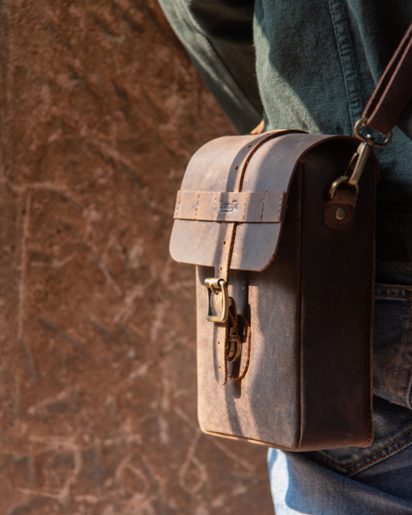Premium leather sling bag with quick-release mounting (motorcycle compatible), one-click opening, and included rain cover. Handcrafted and built to last, developing a unique patina over time. Perfect for everyday carry and more.