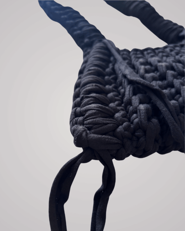 This handcrafted black crochet bag combines style and function. Made from soft t-shirt yarn, it easily transitions from shoulder to handbag.