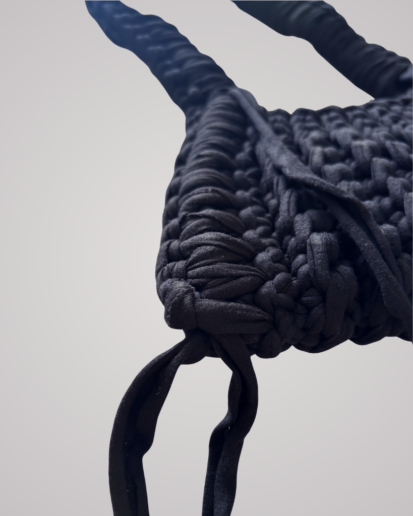 This handcrafted black crochet bag combines style and function. Made from soft t-shirt yarn, it easily transitions from shoulder to handbag.