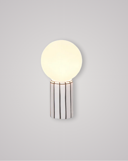 Small porcelain lamp with black vertical lines and a satin white globe on top.